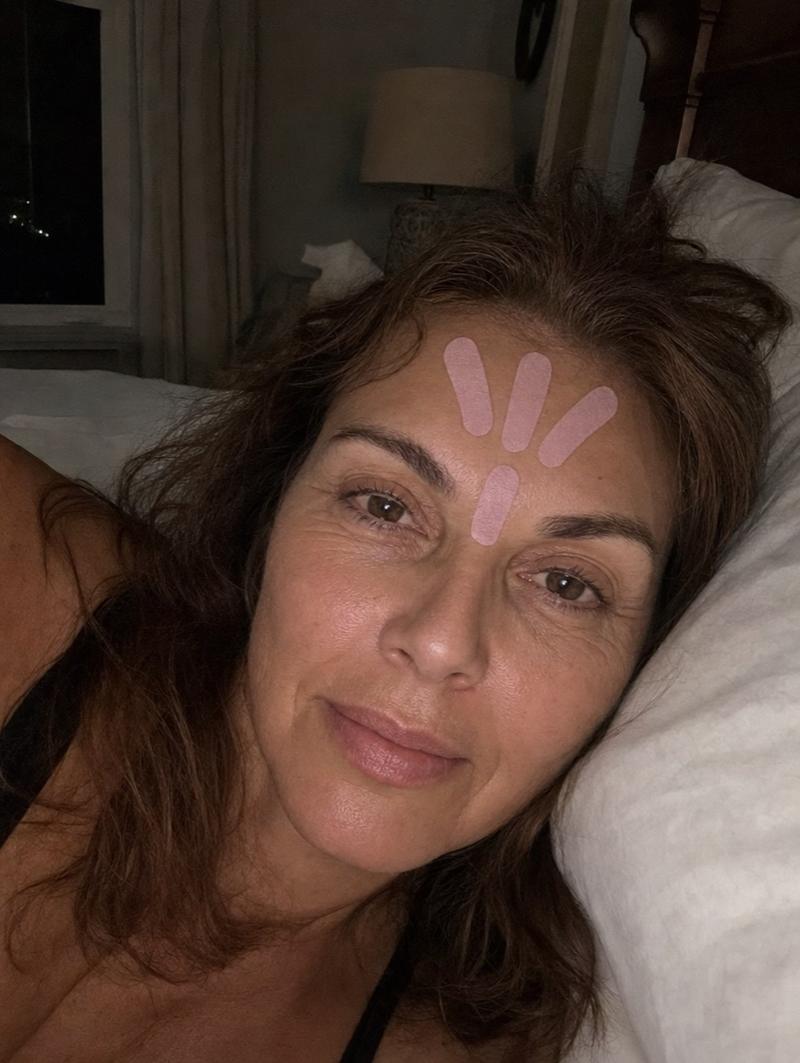 Frau abends im Bett mit Face Tapes auf der Stirn